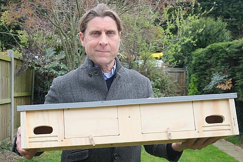 Cllr Tony Harwood with a swift box ready to mount